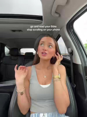A woman is seated in the driver's seat of a car, looking upward to her right and speaking. Overlaid text reads, "go and read your Bible stop scrolling on your phone."