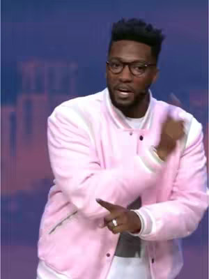 The cover image shows a Black man speaking to the camera. He has a dark afro and is wearing glasses, a white shirt, and a pink jacket. The background is an out-of-focus scene of blurred purple and blue colors.