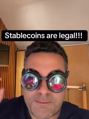 A man wearing unique goggles with colorful reflective lenses is centered in the frame. At the top, a black banner displays the text 'Stablecoins are legal!!!'
