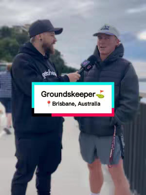 Two men standing outside, one holding a microphone and interviewing the other. A text overlay identifies them as a groundkeeper in Brisbane Australia.