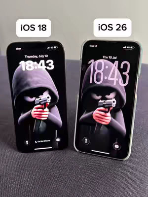 The cover image shows two iPhone screens side-by-side, each displaying a dark-themed wallpaper of a cartoon figure in a black hoodie holding a gun, with the time '18:43' displayed. Above the phones, text bubbles label the screens 'iOS 18' and 'iOS 26'. The image suggests a comparison of wallpaper availability or design across different iOS versions.