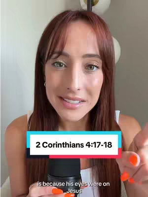 A woman with long brown hair and a white top is in a selfie-style video. A text overlay reads "2 Corinthians 4:17-18". The lighting appears to be soft and natural, with a blurred background featuring a lamp.