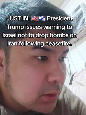 A selfie-style video image with a man's face, presented closely from the chest up, with text overlayed at the top left. The man is looking intently towards the side. The background appears to be a nondescript room with white-colored walls and fixtures.