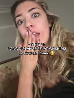A woman with long blonde hair, wide eyes, and her hand covering her mouth, suggesting surprise. Text overlays read 'Calling all: LONG DISTANCE RELATIONSHIPS! Look what I found'. The background is slightly blurred, suggesting an interior setting.