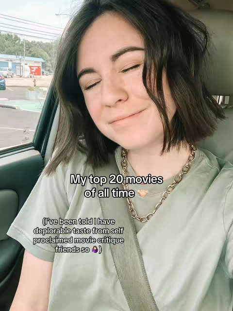 A woman with dark hair and a light green shirt is sitting in a car with her eyes closed and a slight smile. Text overlays the image stating 'My top 20 movies of all time' and a comment about her opinions.