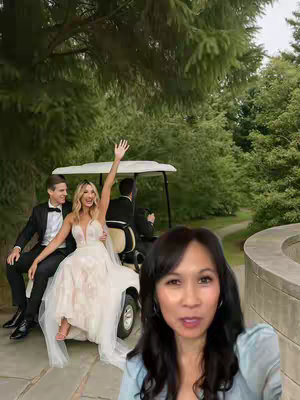 A woman with dark hair is in the foreground, smiling as she speaks to the camera. Behind her, a wedding scene unfolds: a bride waves from a golf cart with a groom beside her. Lush green trees and a stone path form the background.