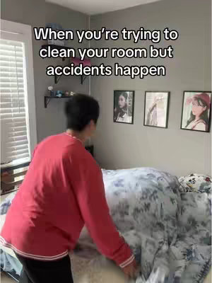 A person in a red sweater is about to make a bed in a gray room. The hook text floats at the top of the image and there are framed pictures on the wall.