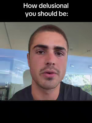 A close-up shot of a man's face. He is looking towards the viewer, with a neutral expression. The background is blurred, showing a glimpse of the outdoors, including some trees and bright sky. Text overlay in the upper part of the screen with the question, 'How delusional you should be:'