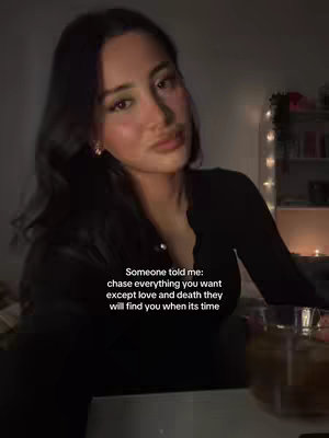 A young woman with dark hair and a subtle makeup looks directly into the camera. Text overlay is present, conveying a reflective quote against a softly lit background. The composition creates a personal and intimate atmosphere.