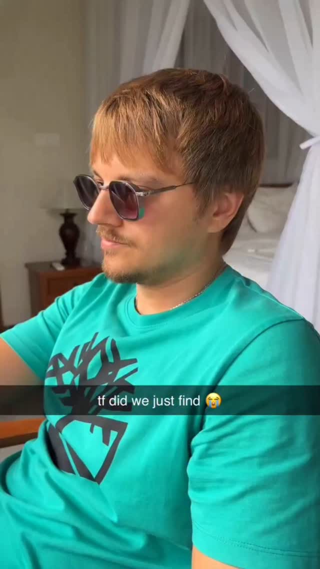 A man with short brown hair and sunglasses is shown in profile. The man is wearing a teal t-shirt.  Text is displayed in a black bar at the bottom of the image.