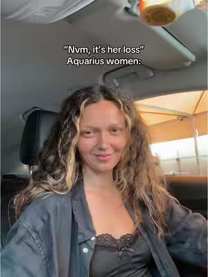A woman sitting in a car smiles at the camera. Text overlays state "Nvm, it's her loss" and "Aquarius women:"