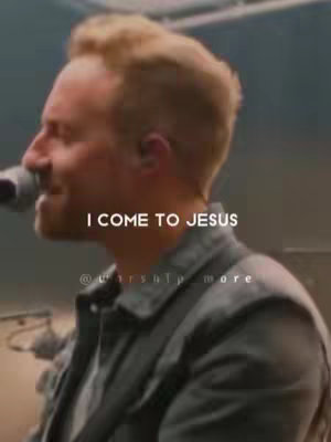 A man with light hair and a beard looks at the ground smiling slightly with a microphone in front of his mouth. Text is overlayed at the bottom of the image.