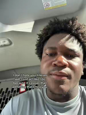 A selfie of a non-white man with curly hair indoors, slightly angled up. The background is of a vehicle interior. Text overlayed on the image.
