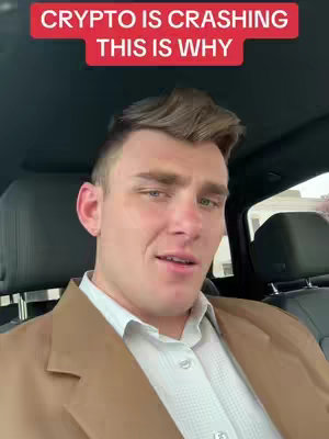 A man in a tan blazer and white shirt is sitting in a car, looking at the camera. Above him is a red bar with white text that reads 'CRYPTO IS CRASHING THIS IS WHY'. The background is a blurred interior of the car.