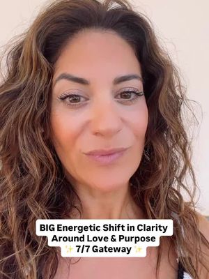 A selfie-style shot features a woman with long, wavy brown hair. She is positioned in the center, looking towards the camera with a soft, inviting expression. Text in a rectangular box at the bottom states: 'BIG Energetic Shift in Clarity Around Love & Purpose 7/7 Gateway'.