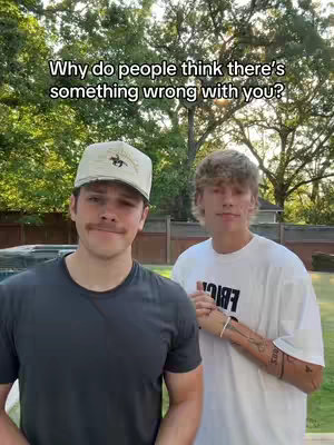 The cover image shows two young men posing outdoors. The man on the left is wearing a hat and a dark t-shirt. The other man is wearing a white t-shirt. The background includes trees and a glimpse of a building.