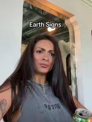 The cover image features a woman in a casual indoor setting. She's facing the camera with a somewhat pensive expression, holding a can of green-labeled beverage. The top has some text that cannot be read (possibly 'Vagazine'), a silver chain necklace and tattoo visible on her left arm. The background includes architectural details like archways and a warm light source.