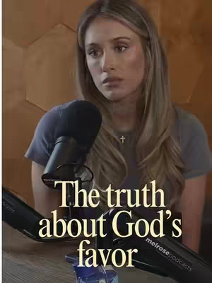 The cover image features a woman with long blonde hair, positioned slightly off-center. She's wearing a gray top and a cross necklace. In the lower section, a microphone is visible in the foreground, and below it, white text overlayed spells out the title.