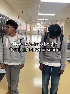 Two young men stand in a school hallway. The one on the left is facing left, wearing glasses, a grey hoodie and his backpack. The other man is facing forward, with his head down, also wearing Backpack and grey hoodie. The text overlay is in white with a black ninja emoji, suggesting a humorous comparison.