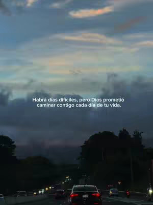 The image captures a road scene with a dark sky and overlayed text. Dark car silhouettes populate the road, moving towards the viewer, while streetlights cast a soft glow. The background features a cloudy, dusky sky.