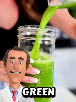 A close-up shot of a green smoothie being poured into a clear glass. A cartoon figure of a doctor with a white coat and a red tie is in the bottom left, looking towards the glass with a smile. The word 'GREEN' is superimposed on the bottom right of the image in white.