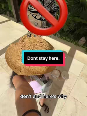 The image shows a person with a straw hat covering most of the frame. The hat is positioned over a light-colored surface, and a red circle with a slash through it is in the upper corner, over a sign. A text overlay says 'Don't stay here.'