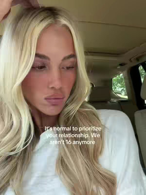 A woman with long blonde hair is in a car. She's looking down and away from the camera. Text overlays in white.