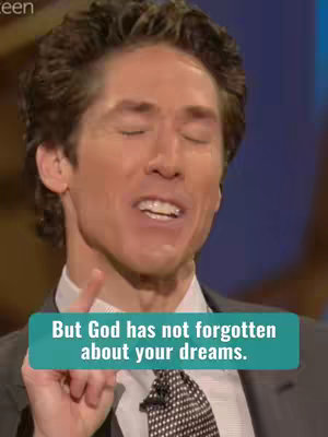 The image features Joel Osteen in a medium shot, with a slightly upward angle. He's indoors, likely on a stage or in a studio, as suggested by the blurred blue background. He's wearing a dark suit, a white collared shirt, and a patterned tie. The man is smiling with his eyes closed and a finger pointing up, and there's text overlaid on the image, placed in a speech-bubble-like shape. Overall, the image has a warm, motivational feel.