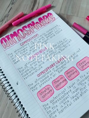 A close-up shot of a notebook page filled with neat handwriting, diagrams, and highlighted text. The title "ATMOSPHERE" is prominently featured in a playful, bubble-letter style, colored with a gradient of pink. The page is divided into sections with clearly defined subheadings, such as "COMPOSITION" and "IMPORTANCE", and includes elaborations of the topic. Highlighters and pens in shades of pink are scattered around the open notebook.