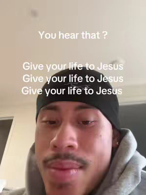 A selfie-style video with the creator's face in the center. The creator is a man, wearing a black beanie and a grey hoodie. Above the creator's head, written in a casual font, is the text "You hear that ?". Below this text, overlapping the creator's head and shoulders, are the words: "Give your life to Jesus" repeated three times.