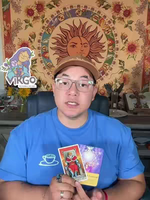 A man wearing glasses and a hat is centered in the frame, holding up two tarot cards and speaking. Behind him is a tapestry with a sun and astrological symbols. To the left is a graphic with the word "VIRGO."