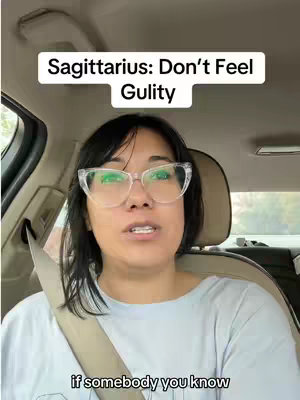 A woman wearing glasses is filmed from the chest up. Her face is centered, and she's seated inside a vehicle. The video is framed to show the inside of the car as well.