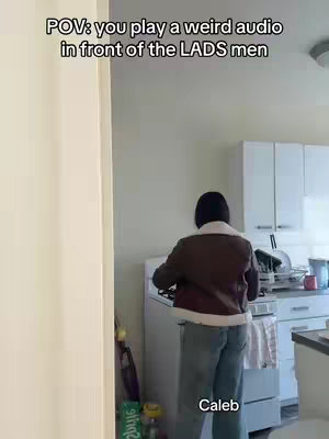 A person is seen from the back, standing in a kitchen. They're wearing a brown and white jacket, along with jeans. There are white cabinets in the background and a stove. Text overlays on the image indicating a 'POV' situation and the name 'Caleb'.