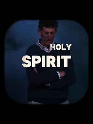 The image features a middle-aged man in a dark sweater and a collared shirt underneath, set against a softly blurred, dark blue background. He is captured from the chest up, with his head bowed and eyes closed, suggesting a moment of prayer or contemplation. Overlaid on the image are large, bold white letters that spell out "HOLY SPIRIT."