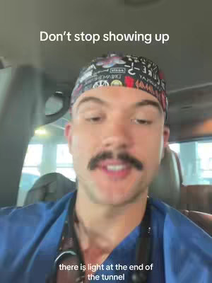 A selfie shot of a man in a blue shirt and a patterned head covering sitting in a vehicle. Text overlays appear at the top that reads "Don't stop showing up" and on the bottom " there is light at the end of the tunnel". The man has a mustache and is looking towards the camera and speaking. The background of the scene is blurred showing car windows and headrests.
