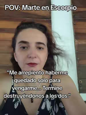 A selfie-style video cover image. A woman with dark hair and fair skin is centered in the frame. Her lips are colored with red lipstick. The background appears to be a wooden structure. Text overlays at the top in white font say 'POV: Marte en Escorpio,' and centered at the bottom, the text says, 'Me arrepiento haberme quedado solo para vengarme... Termine destruyéndonos a los dos.'