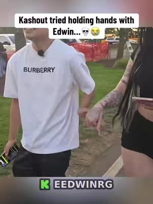 The cover image shows two people holding hands, with one person partially visible on the left wearing a white t-shirt with 'BURBERRY' printed on it, and the other person partially visible from the right side of the image. The background appears to be an outdoor setting with some greenery and a road.