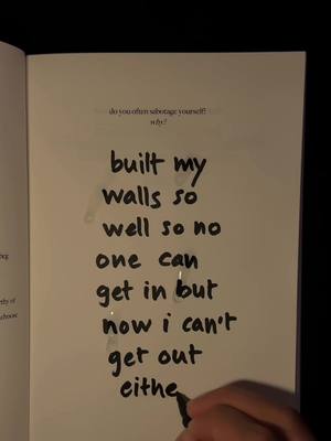 An open book page showing handwritten text in black marker. The text speaks of building walls to keep others out but trapping oneself within.