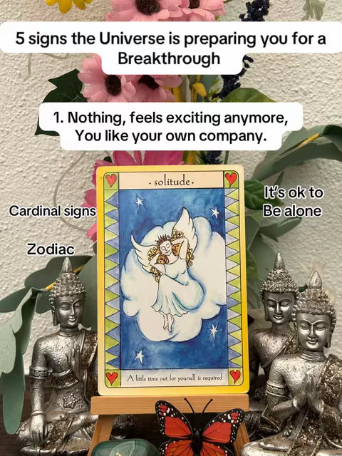 A decorative scene with a tarot card as the central focus. The card shows a drawing of an angel floating on a cloud. Behind it is a mix of greenery, pink flowers, and metallic statues.