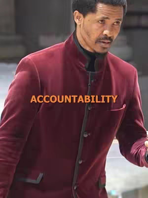A man in a burgundy jacket, focused, with an orange text overlay that reads 'ACCOUNTABILITY.'