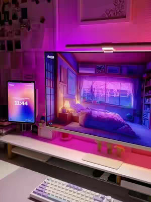 A well-lit indoor scene with a desk setup featuring a large monitor displaying an interior design scene, an iPad on a stand showing the time, a keyboard, and Govee lights behind the monitor emitting a purple hue. The overall composition is centered and tidy, with the room's illumination creating a modern and appealing ambience.
