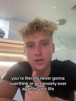 A young man with blonde, textured hair is centered in the frame, facing the camera and speaking. Text is overlaid at the bottom of the image. The background consists of a generic indoor setting, featuring white walls and an overhead light. The composition implies a personal, direct address to the viewer.