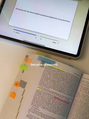 An overhead shot shows a textbook open next to a tablet. The textbook has colorful sticky notes marking text and a highlighter is on highlighting text. The tablet has a question on the screen. The text 'become obsessed.' appears in white at the bottom.