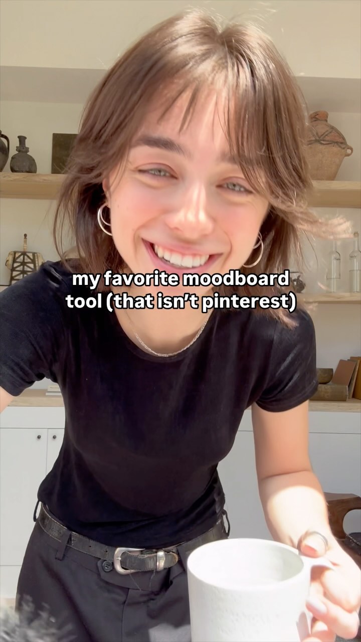 A woman with brown hair smiles at the camera, holding a white mug. Text overlay states 'my favorite moodboard tool (that isn't pinterest)'. The background includes a kitchen setting with natural light.