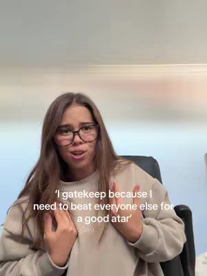 A young woman with long brown hair and glasses is looking directly at the camera and talking with an open mouth, with text overlayed and the background of a wall and a black office chair