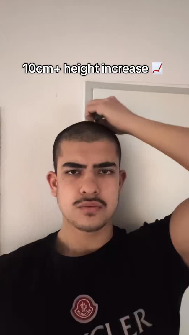 A man with short hair and a mustache is the central figure. He's wearing a black t-shirt with a logo. Text overlayed on the image reads '10cm+ height increase' with a checkmark symbol. He's posing the image, with his hand near the top of his head, as if measuring.
