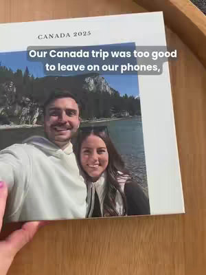 A photograph of a photo album being held, featuring a couple smiling in front of a scenic backdrop of mountains and a lake. Text overlays the image.