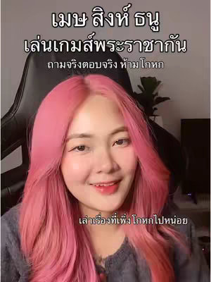 A young woman with bright pink hair smiles at the camera, positioned in the foreground. Text overlays are placed above her and below her face written in Thai. The background appears to be a dark chair and the corner of a room.