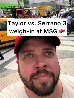 A man in a red cap is taking a selfie in front of a city street scene with trucks and cars, the overlay text reads "Taylor vs. Serrano 3 weigh-in at MSG".