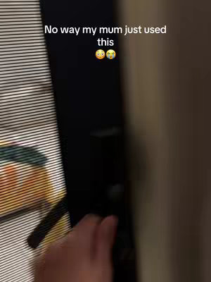 The image shows a hand opening a door. The focus is on the hand and the door, with details like blinds and a wall visible in the blurred background